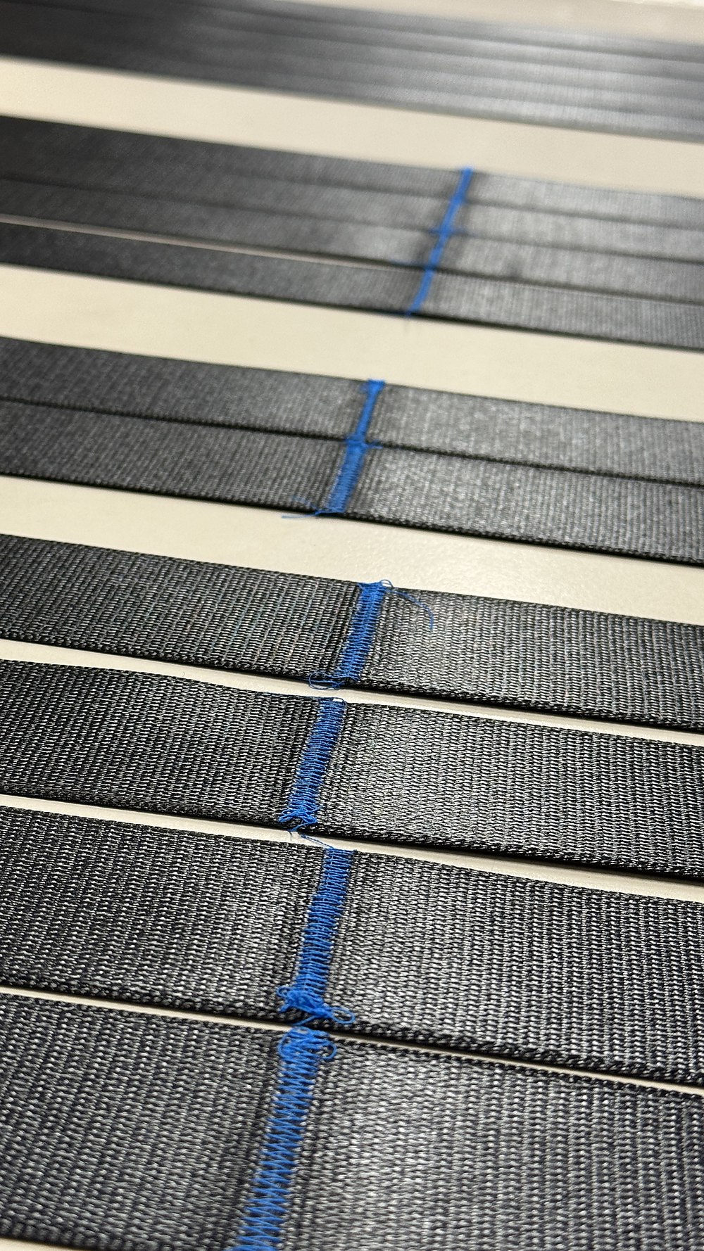 Cross-tack seams sewn in blue thread across the belt webbing