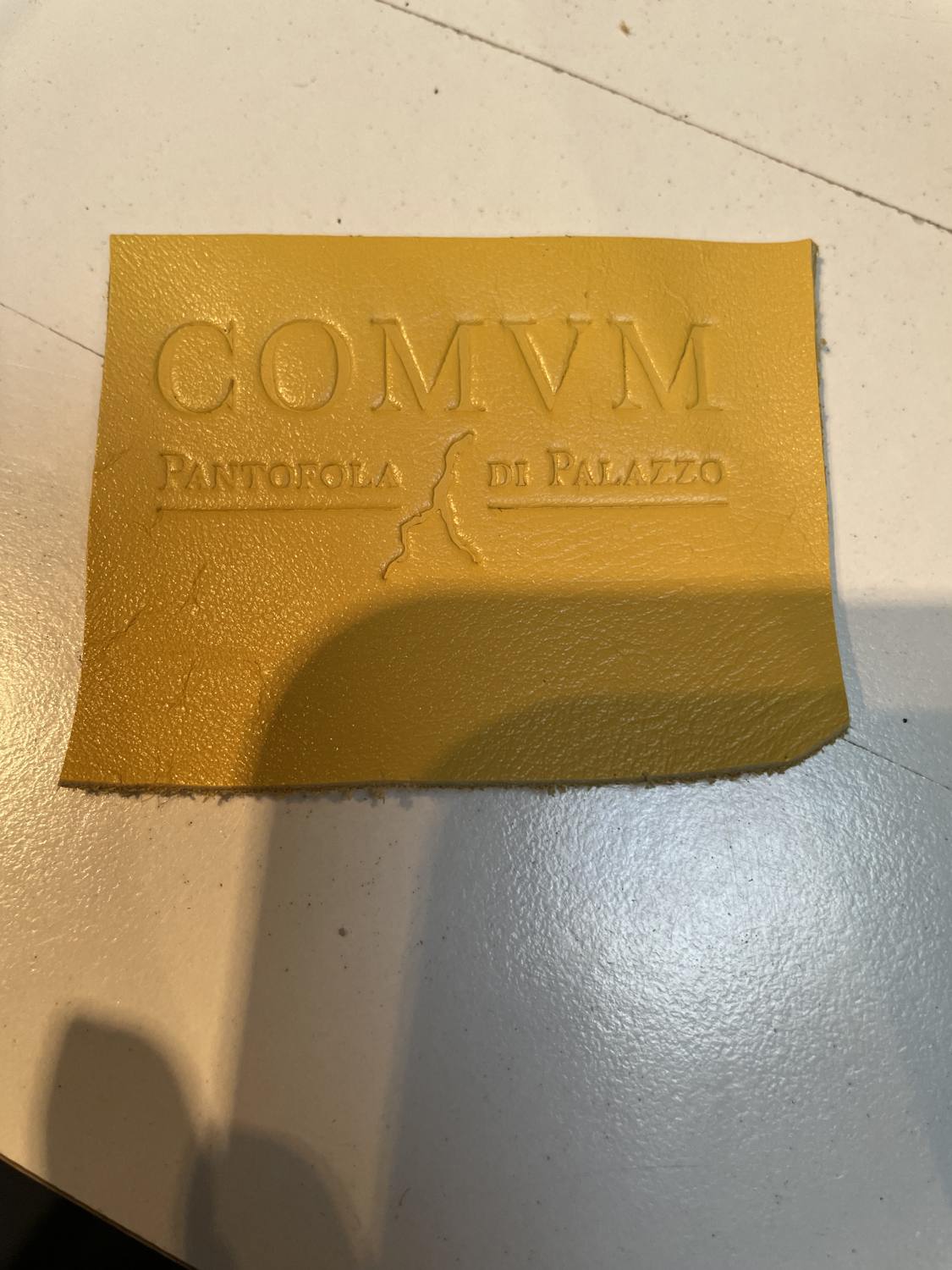 COMVM wordmark blind-embossed into ochre leather