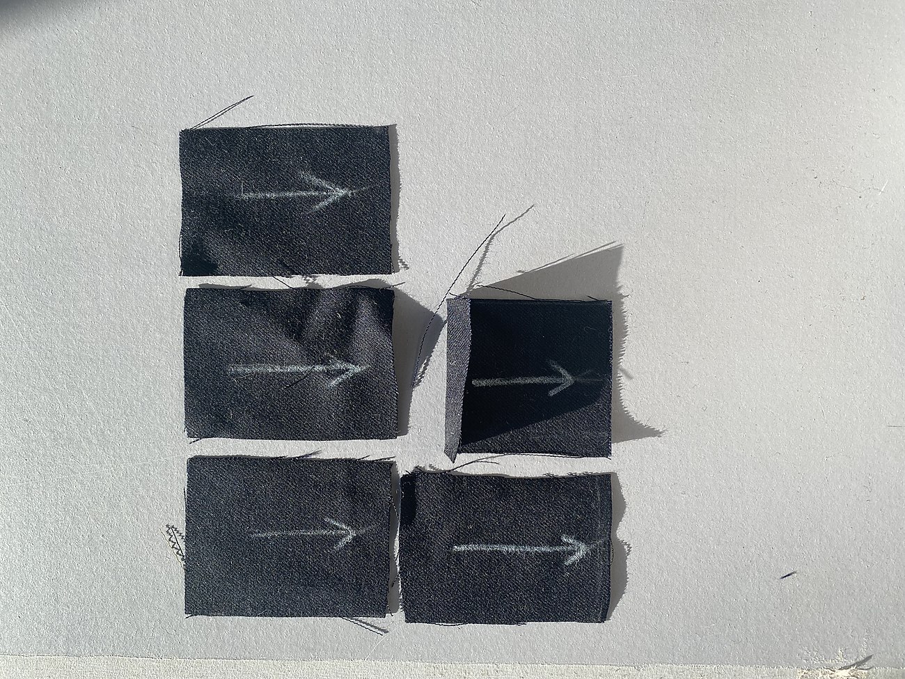 Dark fabric coupons cut and marked with the warp direction