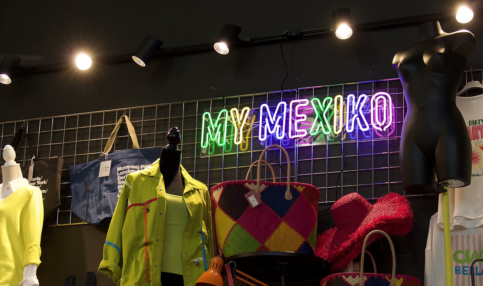 The MyMexiko wall — neon sign above a grid wall with jackets, kilim bags and a straw hat
