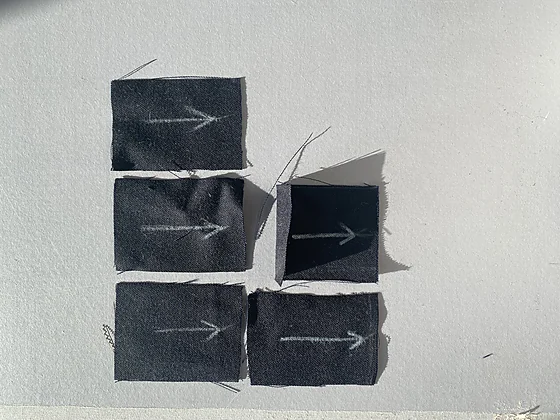 Dark fabric coupons cut and marked with the warp direction